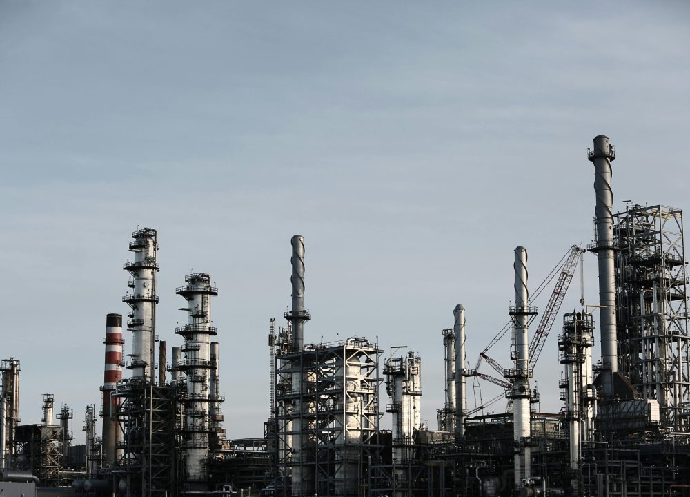 Skyline view of an industrial factory with tall chimneys against a clear sky.
