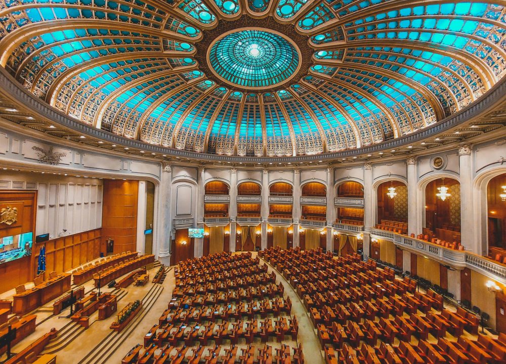 Vibrant interior of a parliament hall with a grand dome and intricate architecture.