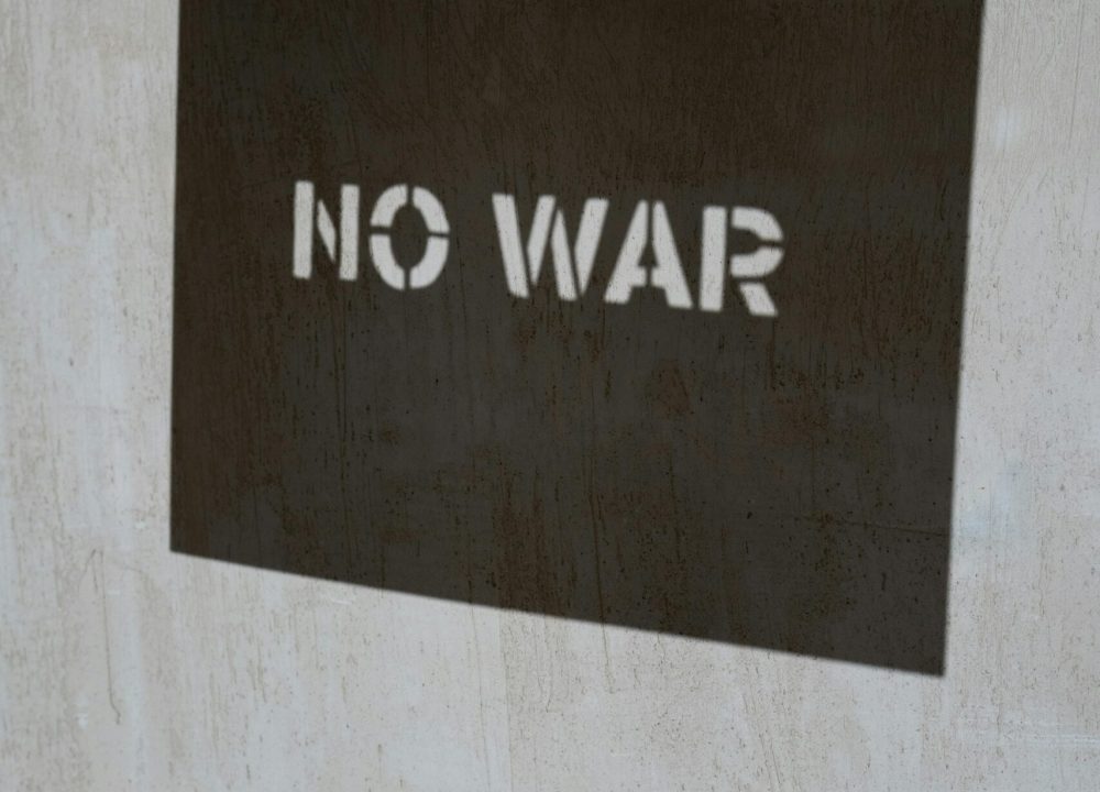 Shadow art depicting 'No War' message on a textured concrete wall, emphasizing peace.