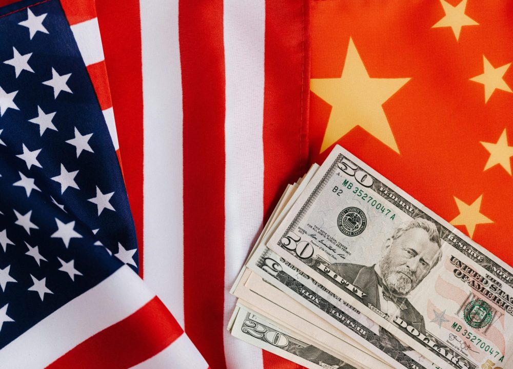 Close-up of US and China flags with US dollar bills, representing international trade and finance.